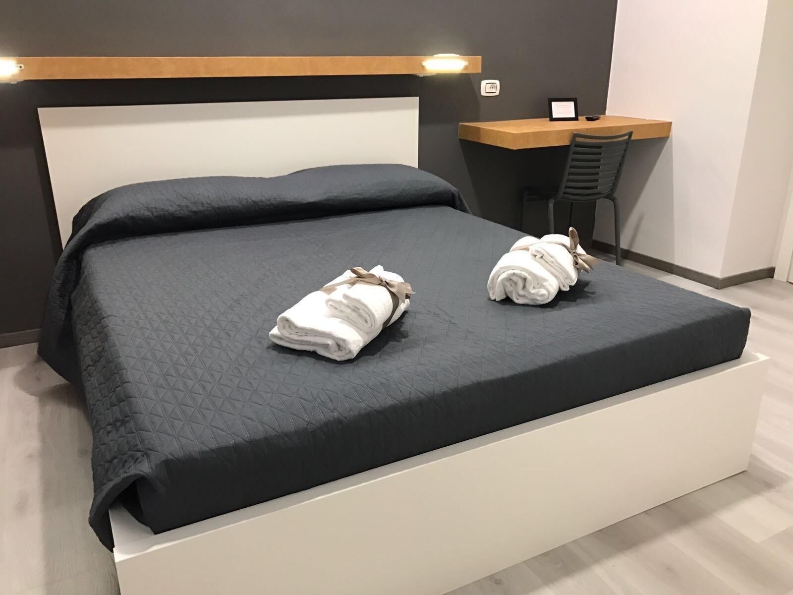 Una habitación de hotel moderna con una cama grande, un escritorio y una silla.