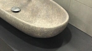 Uma pia de pedra com ralo em um banheiro.
