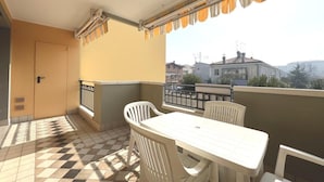 A balcony with a checkered floor, a table, and chairs. - Peaceful Retreat in Grado Close to the Beach (Grado)