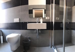 Et moderne badeværelse med toilet, håndvask og glasbrusekabine.