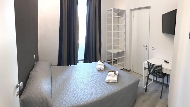 A bedroom with a bed, a desk, a chair, a wardrobe, and a TV. - Economy Room for 1  2 people Piazza San Giovanni (ROMA)