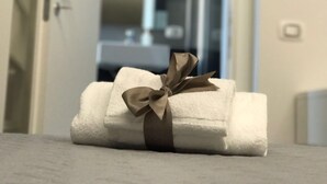 A rolled towel with a brown bow on a marble surface, likely in a hotel room. - Economy Room for 1  2 people Piazza San Giovanni (ROMA)