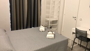 A hotel room with a bed, a desk, a chair, a wardrobe, and a set of curtains. - Economy Room for 1  2 people Piazza San Giovanni (ROMA)
