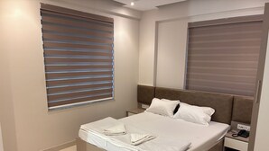 Un dormitorio moderno con cama, mesita de noche y ventana con persianas.