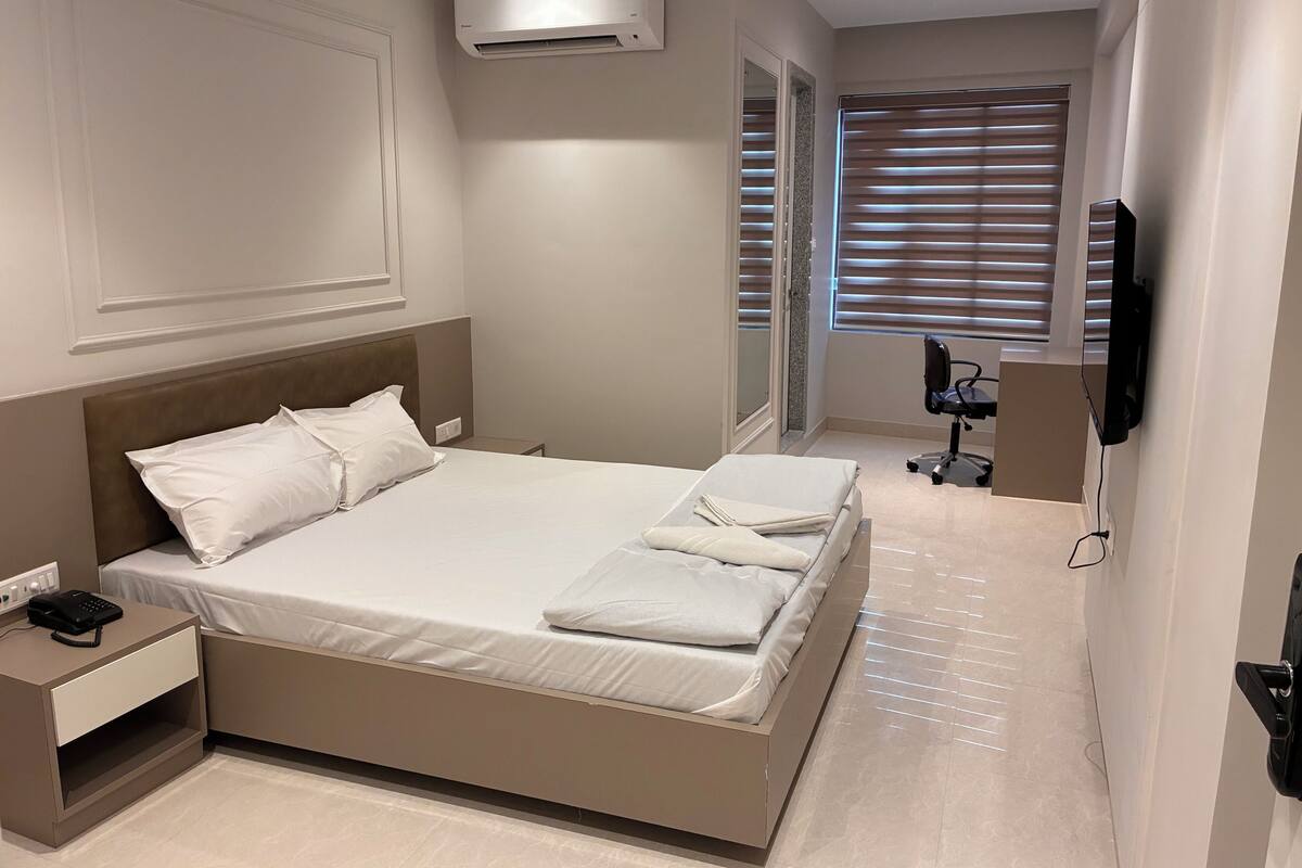 Ein modernes Hotelzimmer mit einem großen Bett, Nachttisch und einem an der Wand montierten Flachbildfernseher.
