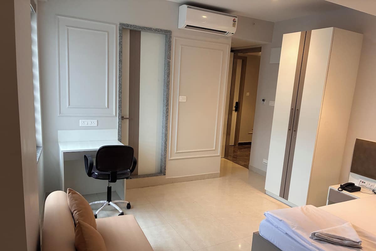 Ein modernes Hotelzimmer mit Bett, Schreibtisch, Stuhl und Kleiderschrank.
