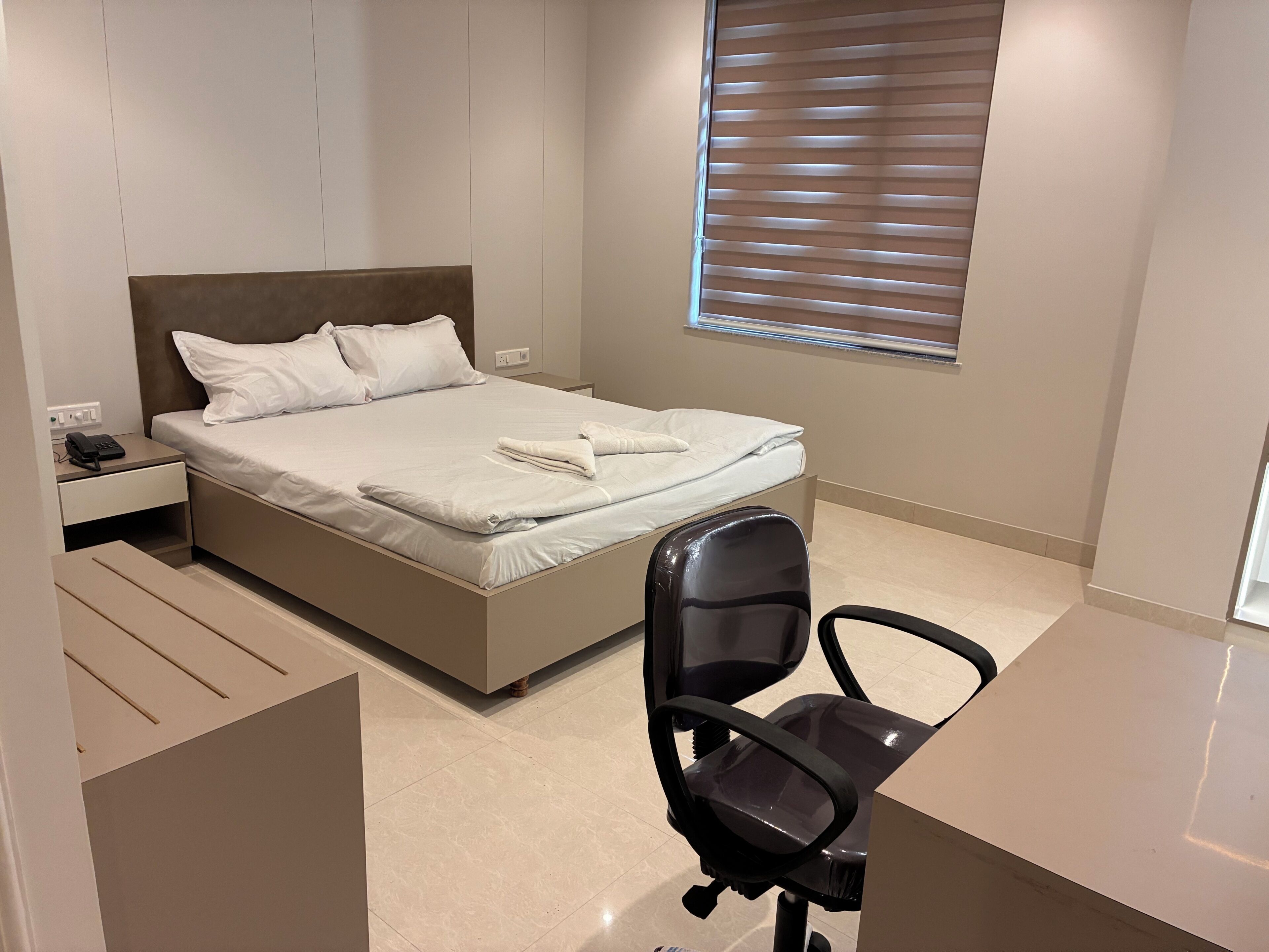 Ein modernes Schlafzimmer mit Bett, Nachttisch und Schreibtisch mit Stuhl.