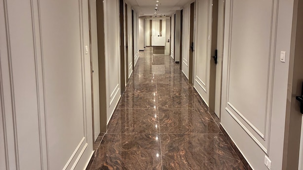 A long, narrow hallway with a polished marble floor, white walls, and doors on both sides. - Swarn Hotel (Kolkata)