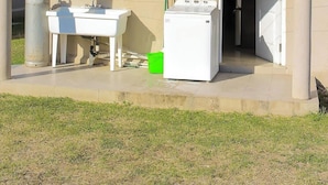 A building with a covered outdoor area, a sink, a washing machine, and a gas cylinder. - Adorable 2-bedroom bungalow with AC in St. Catherine Parish (St. Catherine Parish)