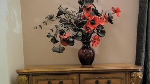 A wooden cabinet with ornate carvings and a vase of flowers on top. - Adorable 2-bedroom bungalow with AC in St. Catherine Parish (St. Catherine Parish)