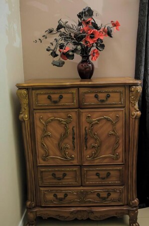 Eine Holzkabinet mit aufwendigen Schnitzereien und einer Blumenvase darauf.