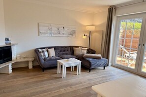 A living room with a sofa, a small table, a lamp, and a painting on the wall. - Beach House Apartment 5 (Westerland\/ Sylt)