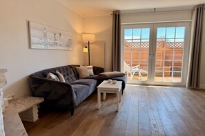 A living room with a dark-colored sofa, a white coffee table, and a painting on the wall. - Beach House Apartment 5 (Westerland\/ Sylt)