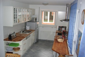 Eine kleine Küche mit weißen Schränken, einem Fenster, einer Mikrowelle und einem Toaster.