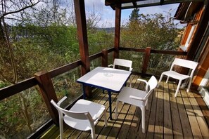 Un terrazza in legno con tavolo e sedie, circondata da una ringhiera di legno.