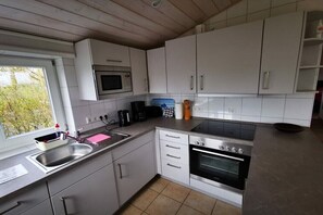 Una cucina moderna con mobili bianchi, un forno a microonde integrato, un piano cottura e un lavello.