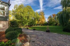 A stone pathway leading to a building with a brick facade, surrounded by well-maintained hedges and trees.