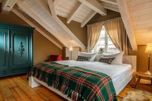 A bedroom with a wooden ceiling, a bed with a plaid blanket, a green cabinet, and a window with curtains.