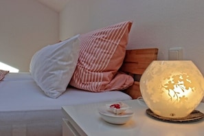 Ein Bett mit Kissen, ein Nachttisch mit Obstschale und eine dekorative Lampe.