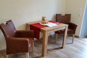 Ein kleiner Raum mit einem Holztisch und zwei braunen Stühlen.