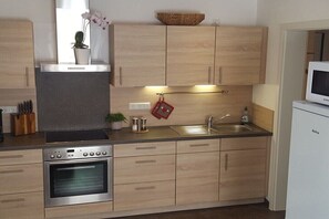 Eine moderne Küche mit Holzschränken, einem Backofen, einer Spüle und einer Mikrowelle.