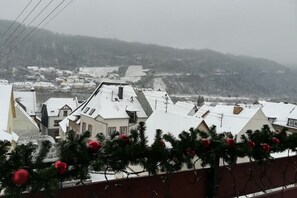 Ein verschneites Dorf mit traditionellen Häusern und Blick auf die umliegenden Hügel.