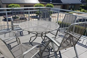Ein Balkon mit einem runden Metalltisch und vier Stühlen, umgeben von einem Metallgeländer.