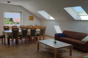 Ein Essbereich mit Tisch, Stühlen, einer Couch und Dachfenstern.