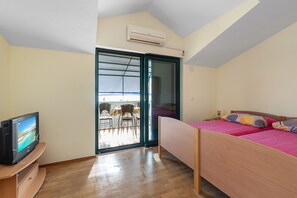 A bedroom with a bed, a TV, a sliding glass door leading to a balcony, and an air conditioning unit. - Angelo Apartment Brodarica 1 (Šibenik-Brodarica)