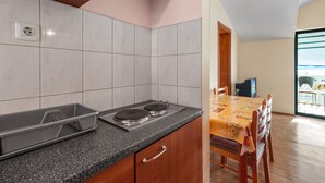 A kitchen with a granite countertop, a stove, and a dining area with a table and chairs. - Angelo Apartment Brodarica 1 (Šibenik-Brodarica)