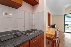 A kitchen with a granite countertop, a stove, and a dining area with a table and chairs. - Angelo Apartment Brodarica 1 (Šibenik-Brodarica)