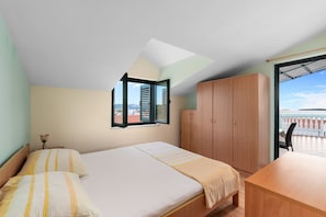Ein Schlafzimmer mit Bett, Kleiderschrank, Schreibtisch und einem Fenster mit Blick.