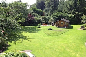 Eine Holzhütte, umgeben von einem gepflegten Rasen und dichtem Baumbestand.