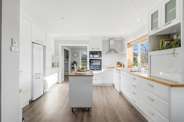 A modern kitchen with white cabinetry, a central island, and a view to the outdoors.