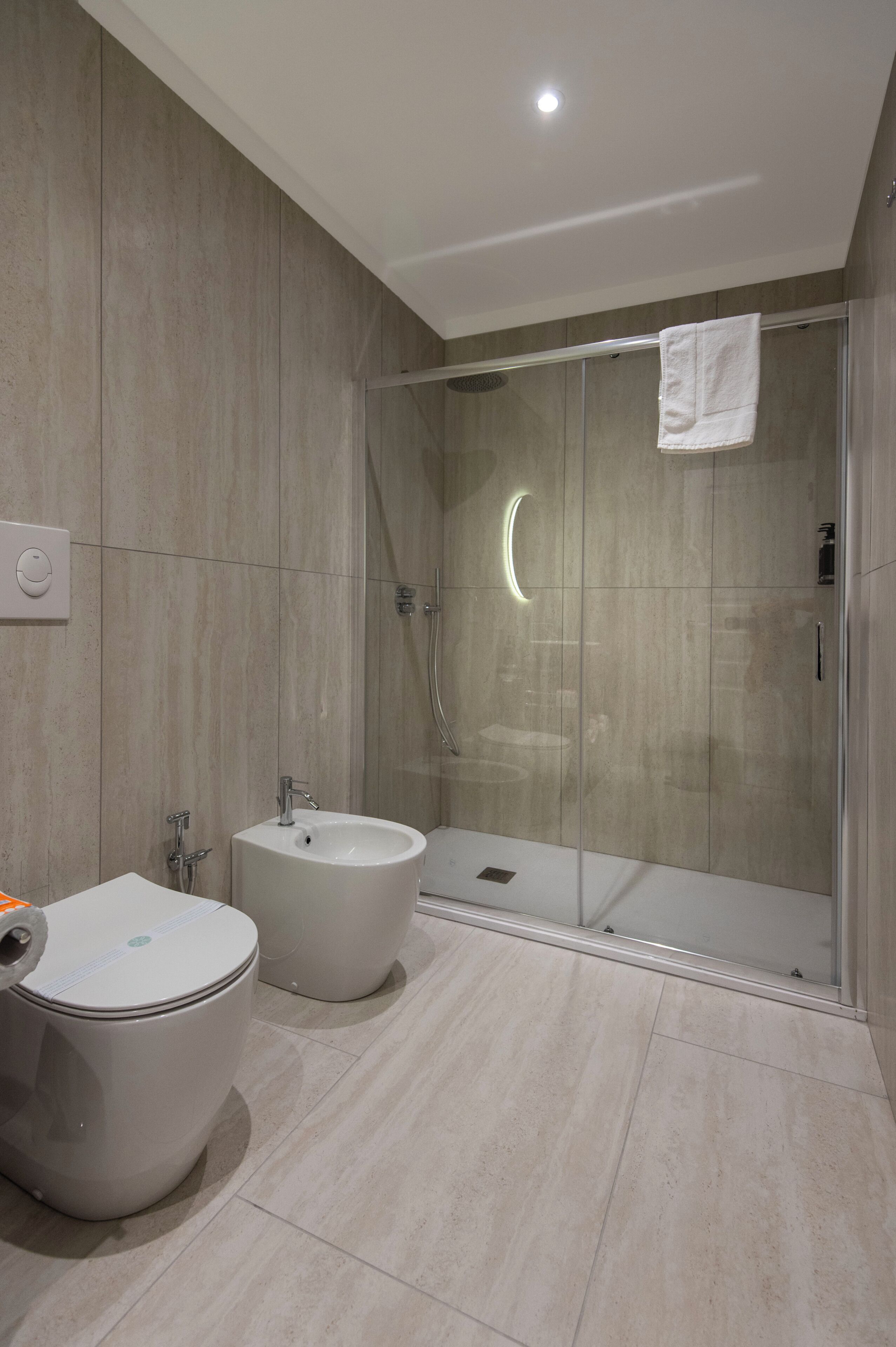 A modern bathroom with a toilet, bidet, and glass-enclosed shower.