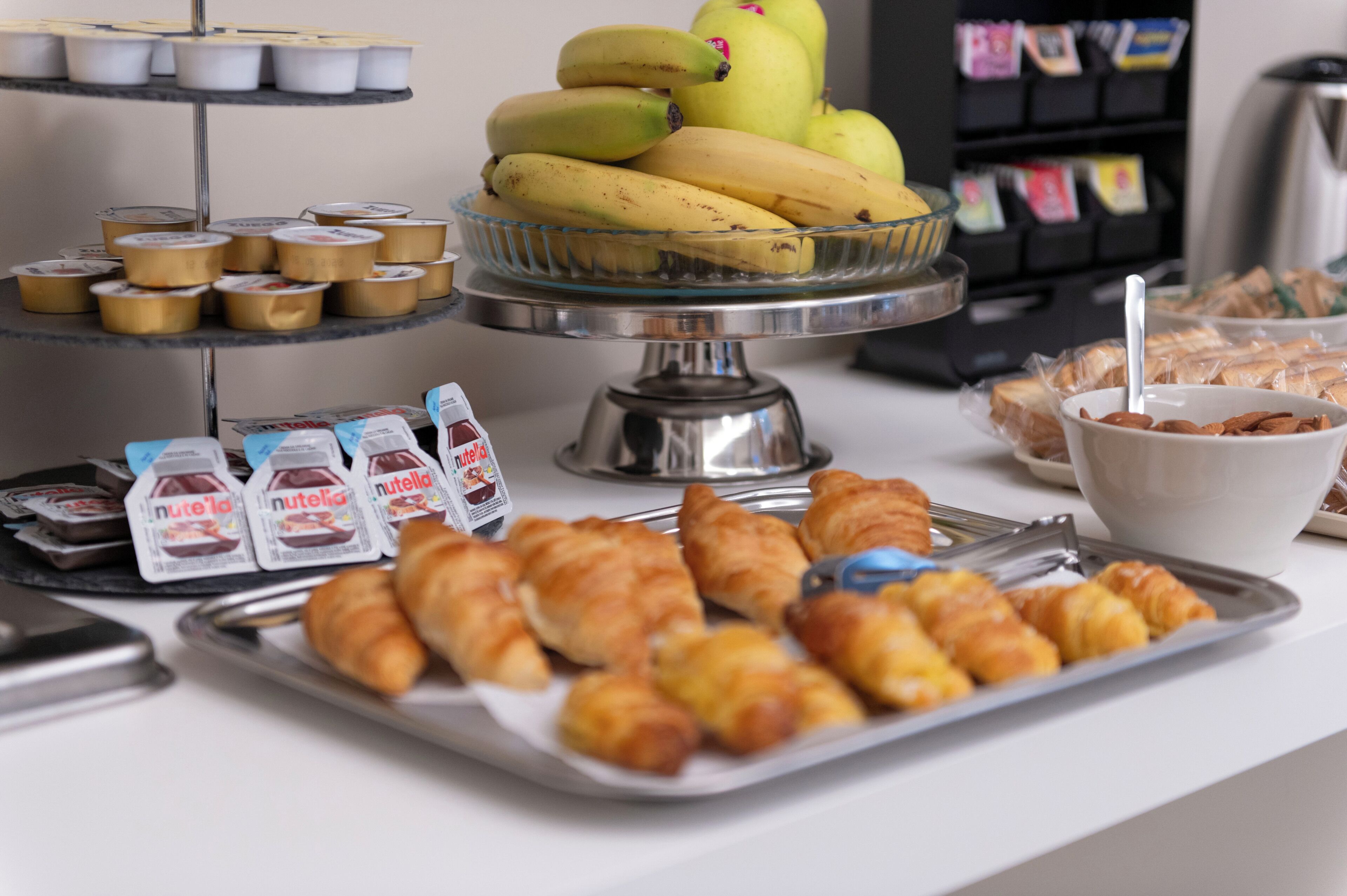 A buffet with various food items including bananas, pastries, and packaged snacks.