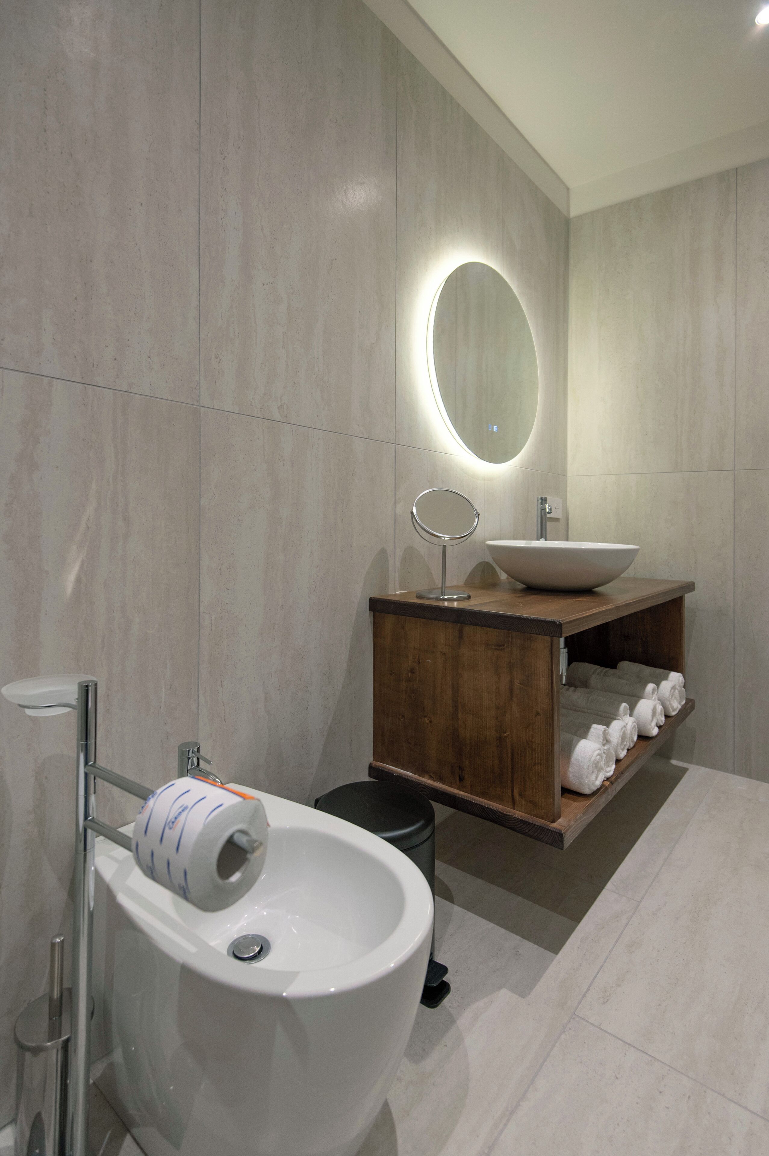 A modern bathroom with a large sink, a mirror, and a wooden vanity.