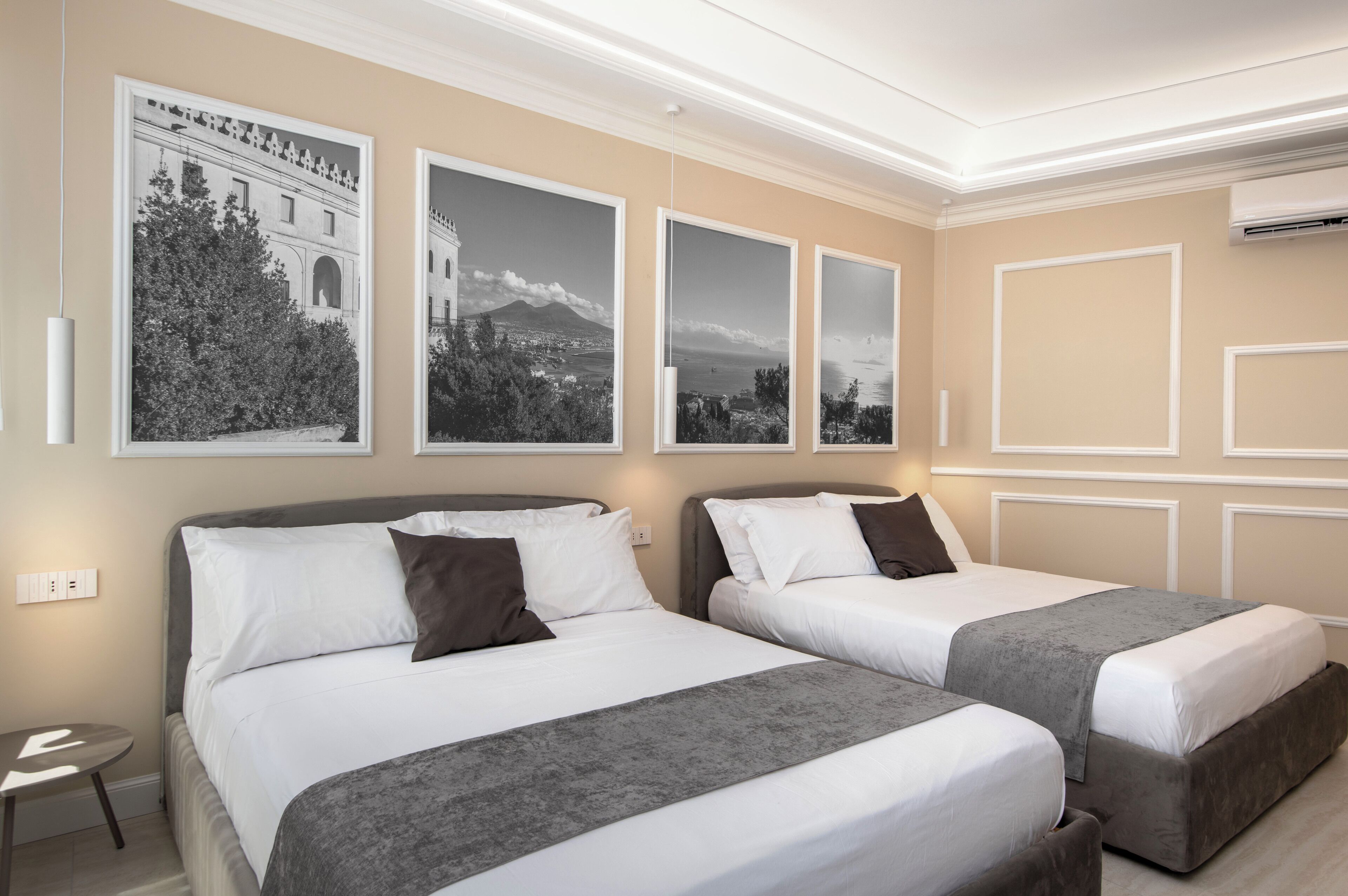 Une chambre d’hôtel avec deux lits, une petite table et trois tableaux encadrés accrochés au mur.
