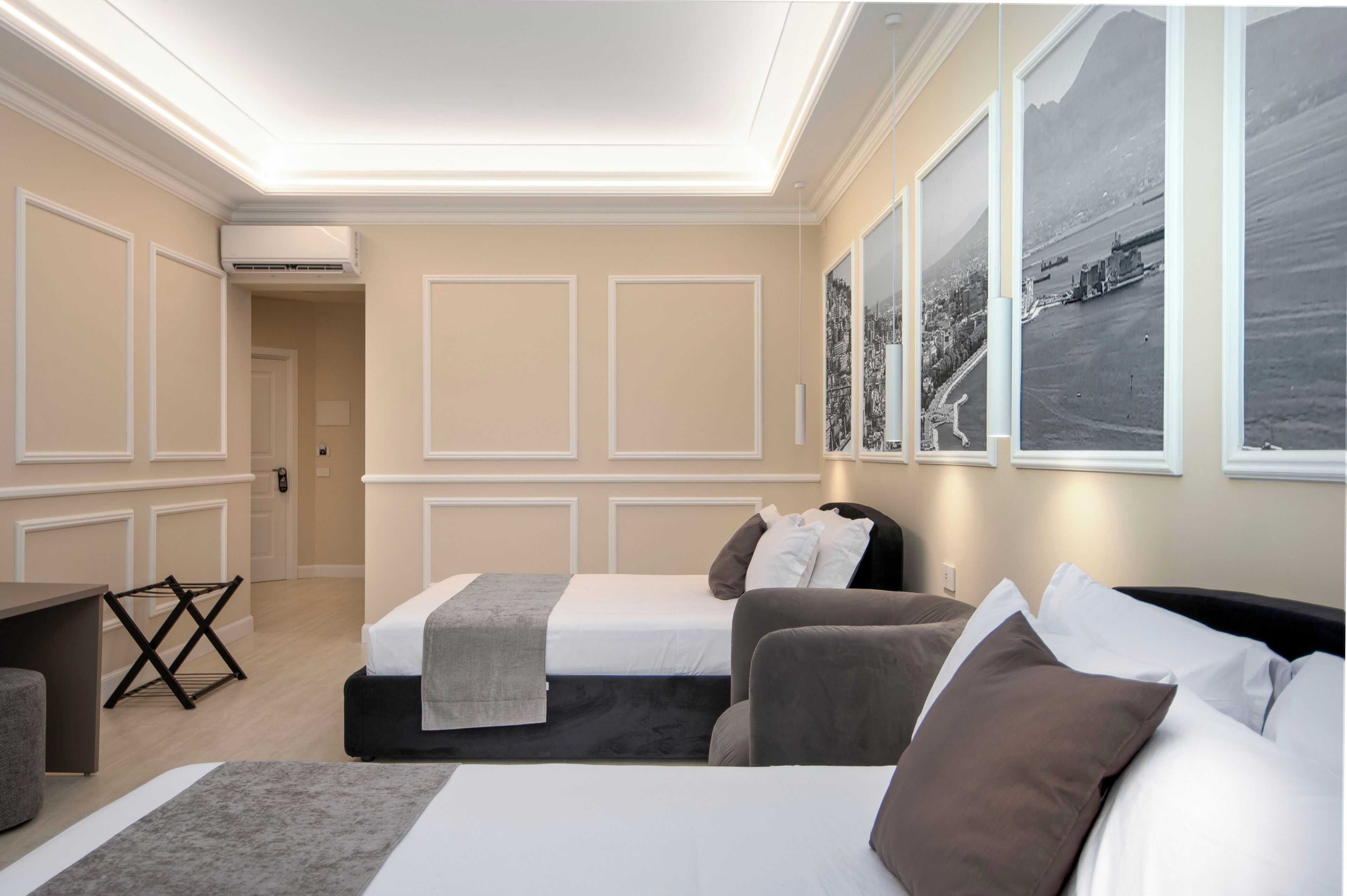 A hotel room with two beds, a desk, and a chair. There are framed pictures on the wall.