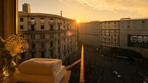 Vista del atardecer desde una ventana con vista a una calle urbana, edificios y un anuncio publicitario.