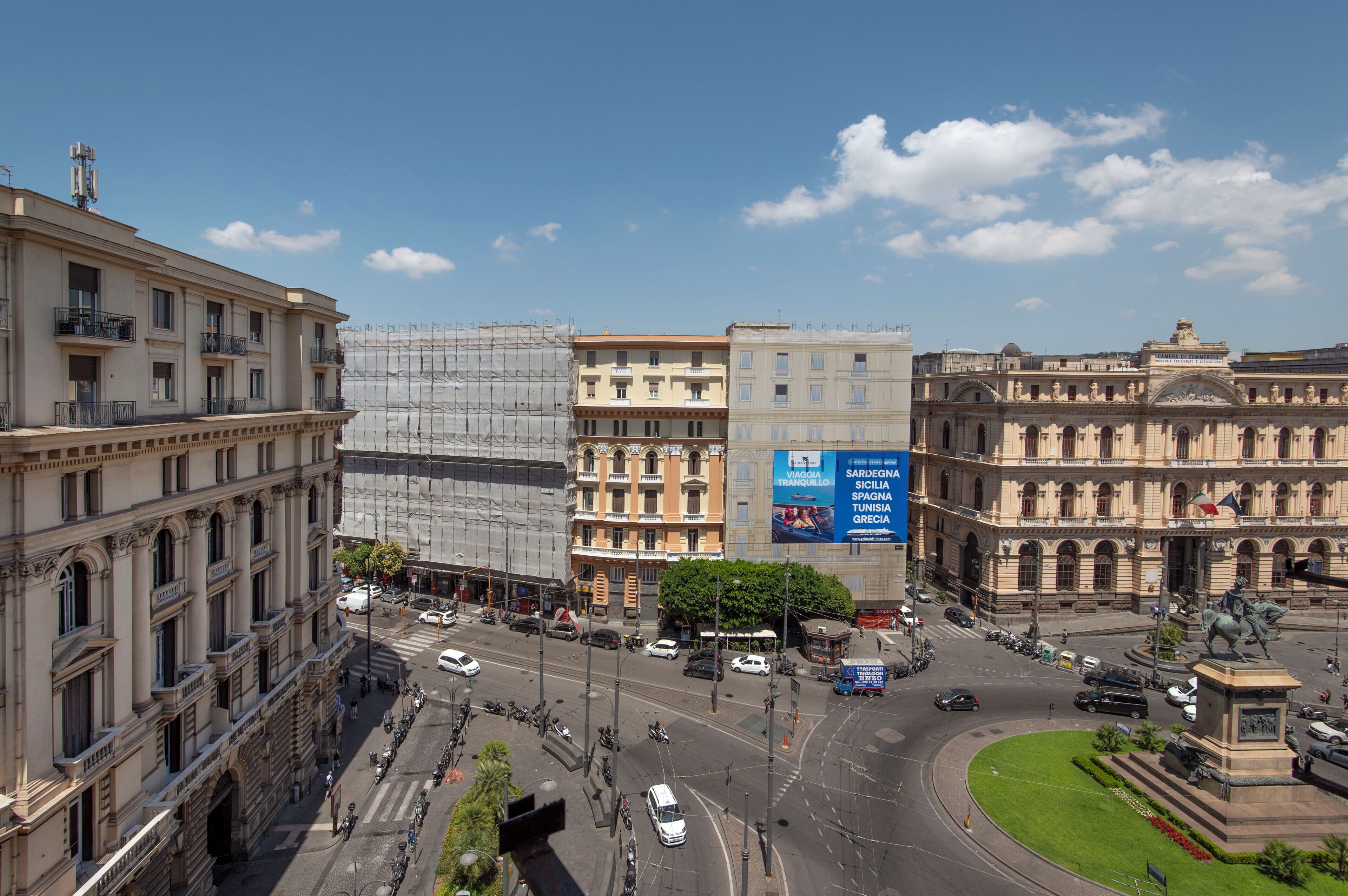 Un paisaje urbano con edificios históricos, una intersección concurrida y una estatua.