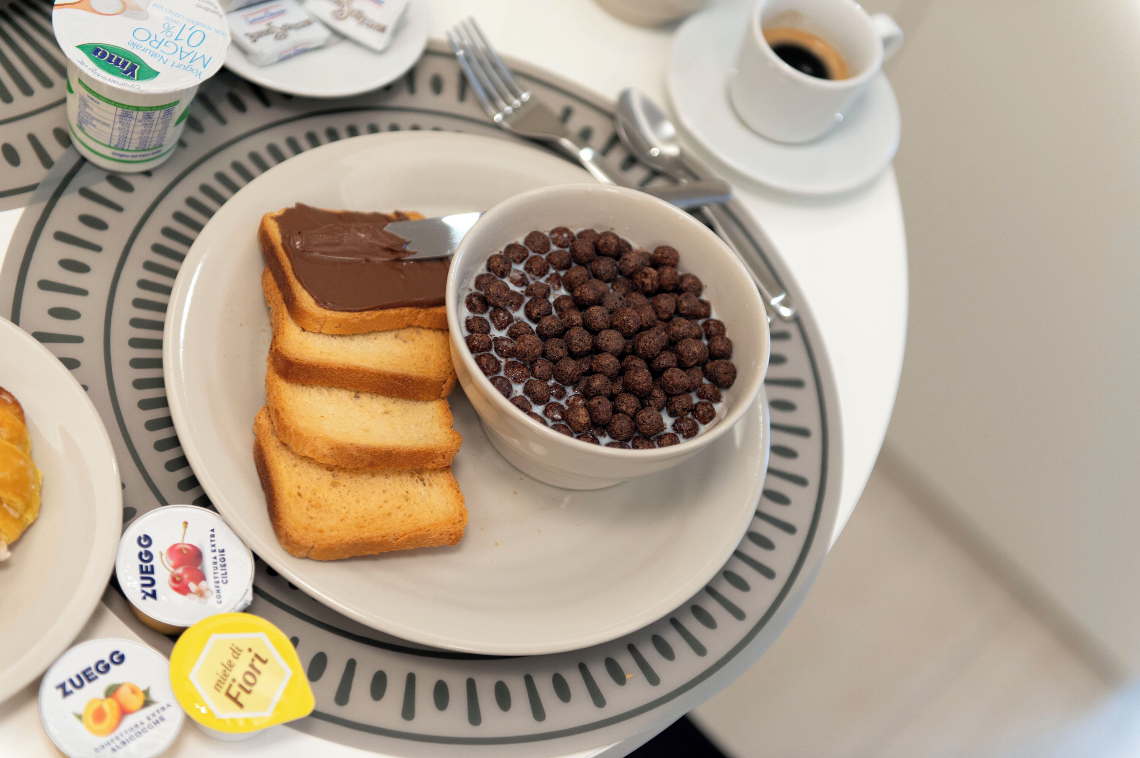 A breakfast setting with toast, chocolate spread, and cereal.
