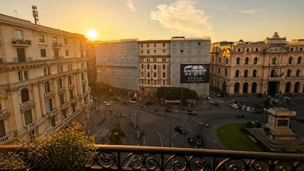 Un paisaje urbano con edificios históricos, una rotonda central y un gran anuncio.