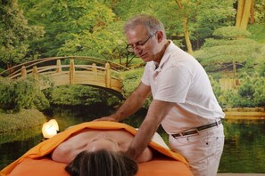 Eine Person bekommt eine Massage in einem Raum mit Blick auf eine Brücke über dem Wasser.