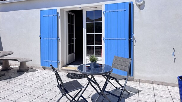 Eine Terrasse mit einem runden Tisch, zwei Stühlen und einem Blumentopf.