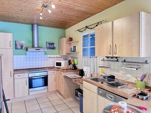 Eine Küche mit Holzschränken, einer Mikrowelle, einem Backofen und einem Spülbecken.