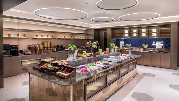 Une cuisine d’hôtel moderne, dotée d’un buffet, d’appareils électroménagers en acier inoxydable et d’un aménagement propre et bien organisé.