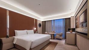Une chambre d’hôtel moderne équipée d’un grand lit, d’une table de chevet, d’un bureau, d’une chaise et d’un téléviseur.