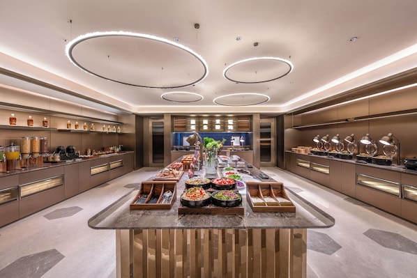 A modern kitchen with a central island, built-in appliances, and a variety of food items displayed.