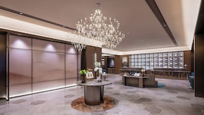 A lobby with a chandelier, a reception desk, and a display of items.